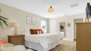 Une chambre à coucher avec un grand lit, des tables de chevet, une armoire et un luminaire au plafond.