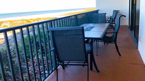 Un balcon avec une table et des chaises, donnant sur une plage.