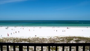 A beach with people, a clear sky, and the ocean.