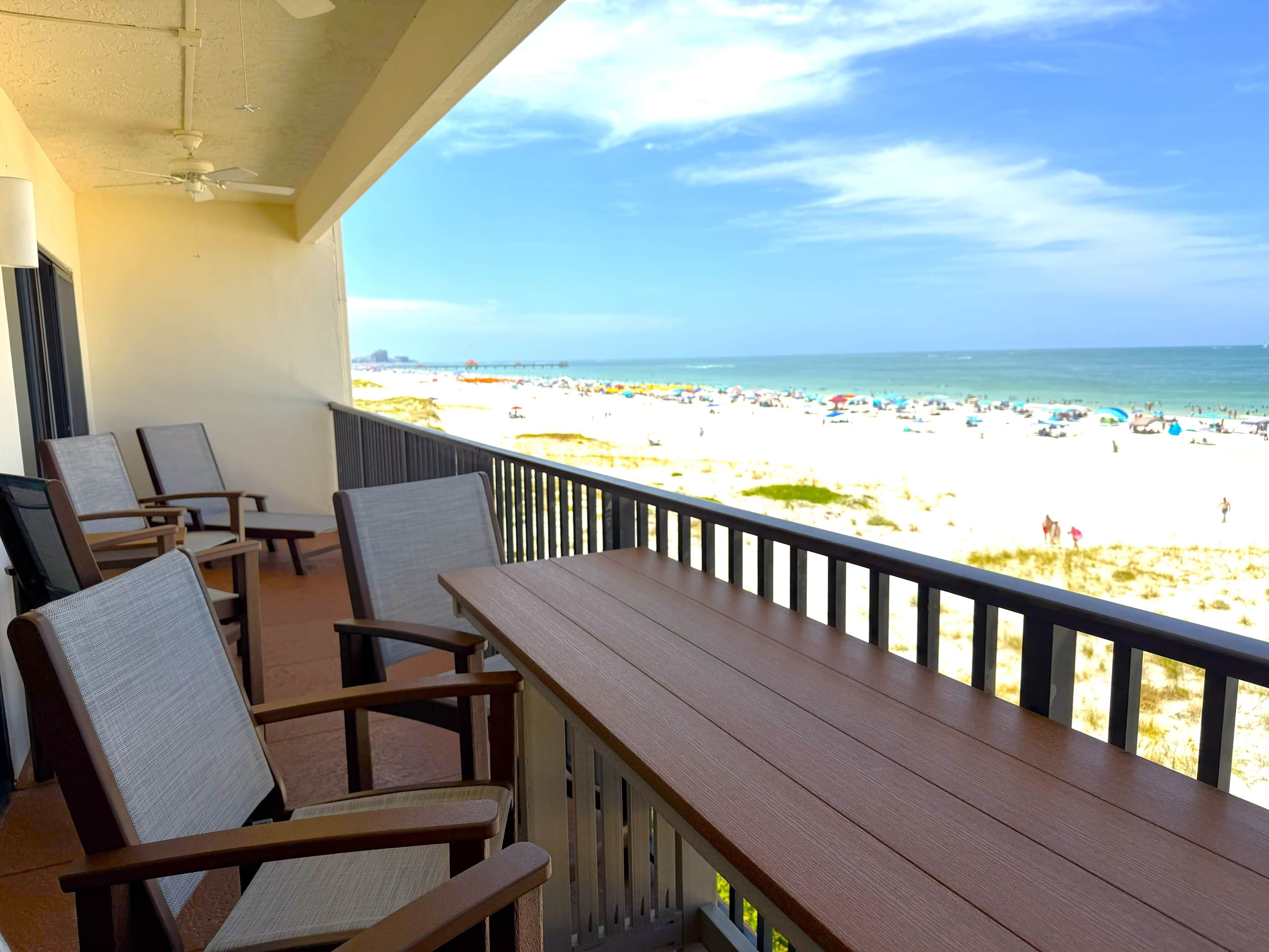 Un balcone con vista sulla spiaggia, mobili in legno e una ventola a soffitto.
