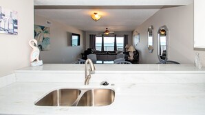 A modern kitchen with a large island, stainless steel sink, and a ceiling fan. - Surfside 503 - 2 Bedroom 2 Bath Oceanfront Condo (Clearwater)