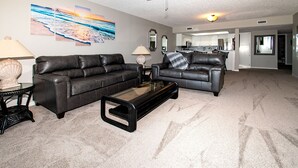 A living room with two leather sofas, a glass coffee table, and a large abstract painting on the wall. - Surfside 503 - 2 Bedroom 2 Bath Oceanfront Condo (Clearwater)