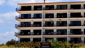 Un hôtel à plusieurs étages doté de balcons, situé près d’une plage.