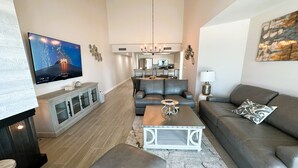 Una sala de estar moderna con un televisor de pantalla plana, sofás grises, una mesa de centro y una chimenea.