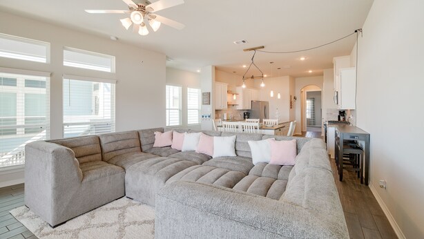 A spacious living room with a sectional sofa, a ceiling fan, and a kitchen area in the background. - Bay-View La Porte Home Rental: Steps to Beach! (La Porte)