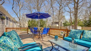 An outdoor patio with blue furniture, a table, and an umbrella. - Families Welcome! Home 2 Mi to Craigville Beach (Hyannis)