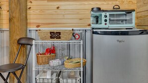 A kitchenette with a toaster oven, a refrigerator, and shelves with baskets and kitchen items. - Farm Stay: Modern Barndominium in Lakeland! (Lakeland)