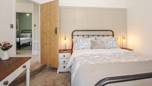 Une chambre à coucher comprenant un lit, des tables de chevet, une armoire en bois et un miroir.