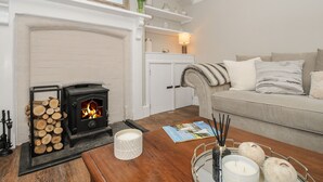 Un salon chaleureux avec une cheminée, un canapé, une table basse avec des bougies et un magazine.