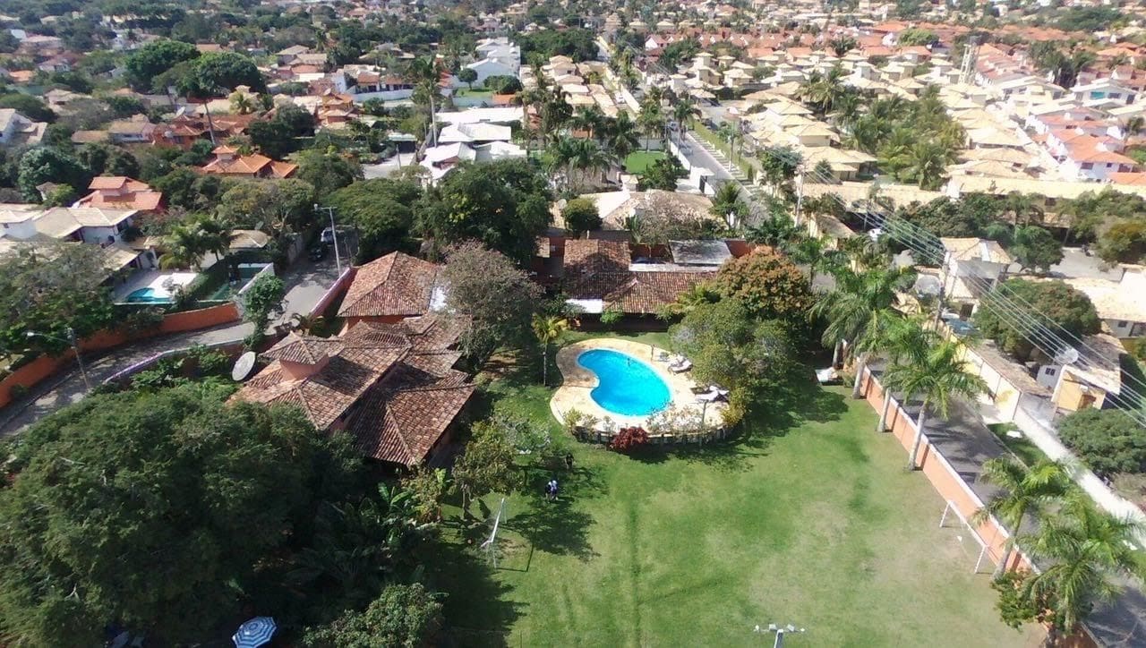 A residential area with a swimming pool surrounded by a lawn and trees.