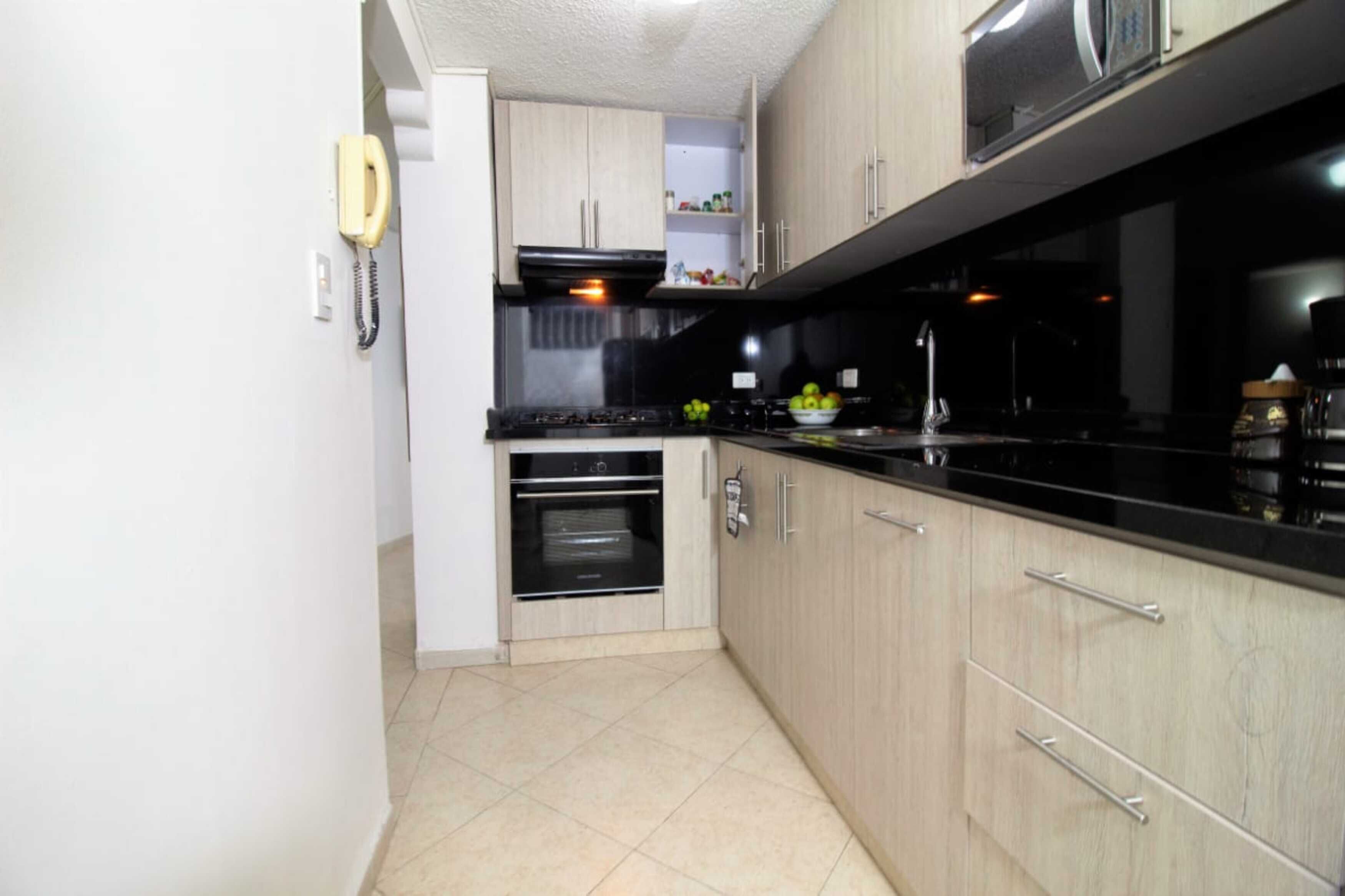 A compact kitchen with a stove, oven, and microwave. There are cabinets and a countertop.