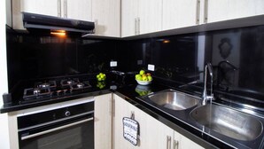 Una cucina con piani di lavoro neri, elettrodomestici in acciaio inossidabile e mobili in legno chiaro.
