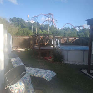 A backyard with a wooden deck, a hot tub, and a pool.