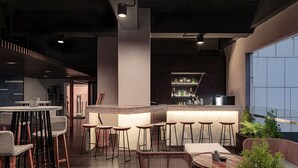 Un espace bar moderne avec des tabourets hauts, un comptoir et un coin salon comprenant une table ronde et des chaises en osier.
