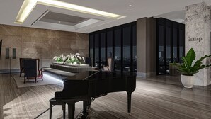 Un intérieur moderne avec un piano à queue, un canapé et une vue sur la ville à travers de grandes fenêtres.