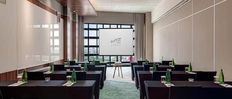 A conference room with tables, chairs, and a projector screen.