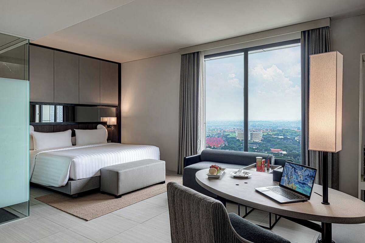 Une chambre d’hôtel moderne équipée d’un lit, d’un canapé, d’une table à manger et d’un ordinateur portable.