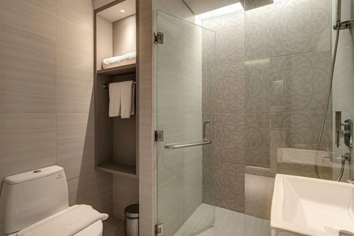 A modern bathroom with a glass-enclosed shower, a white toilet, and a bathtub.