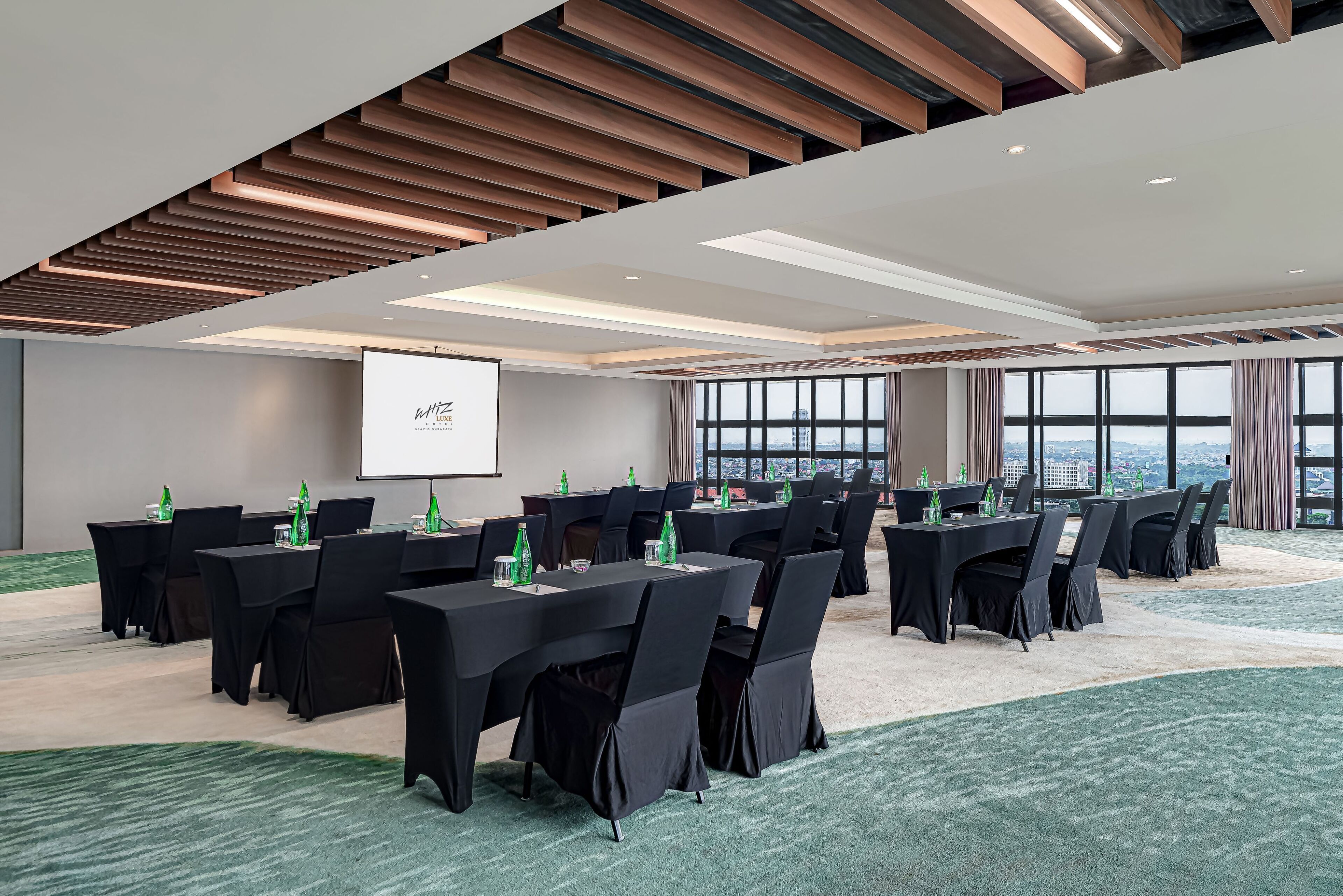Un salón de conferencias con varias mesas, sillas y una pantalla para proyector.