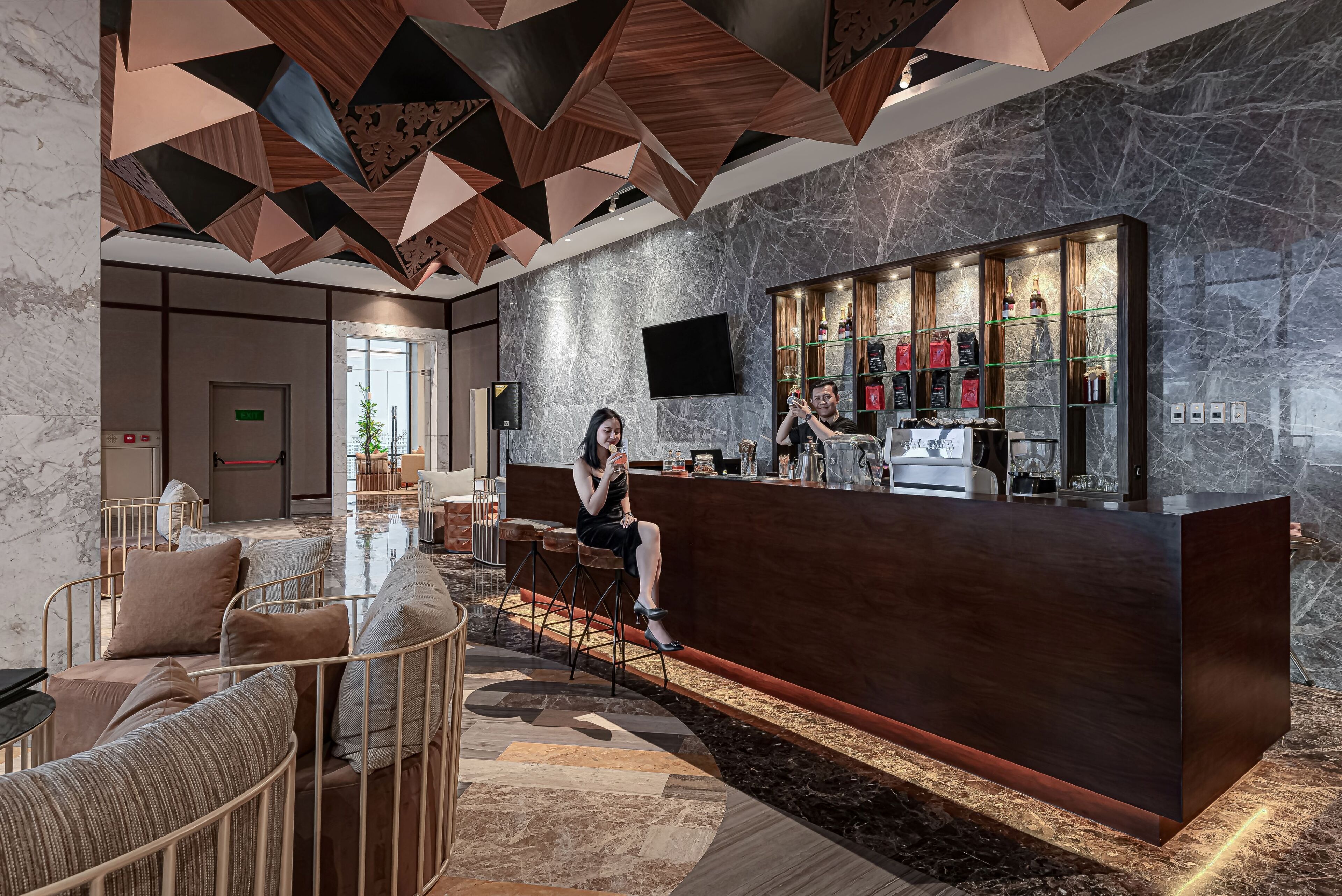 A modern lobby with a reception desk, seating area, and a bar.