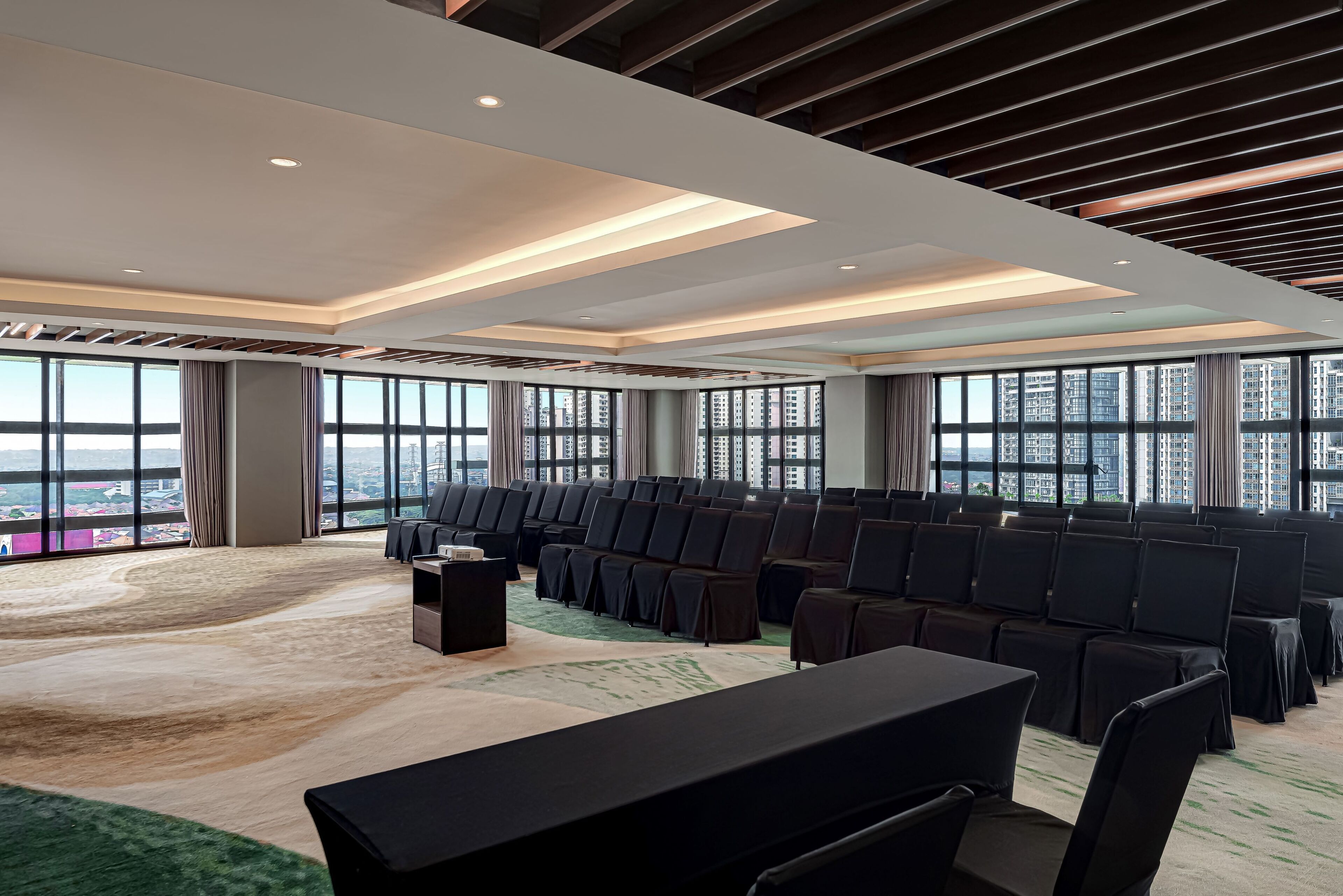 A conference room with rows of chairs, a table, and large windows offering a city view.