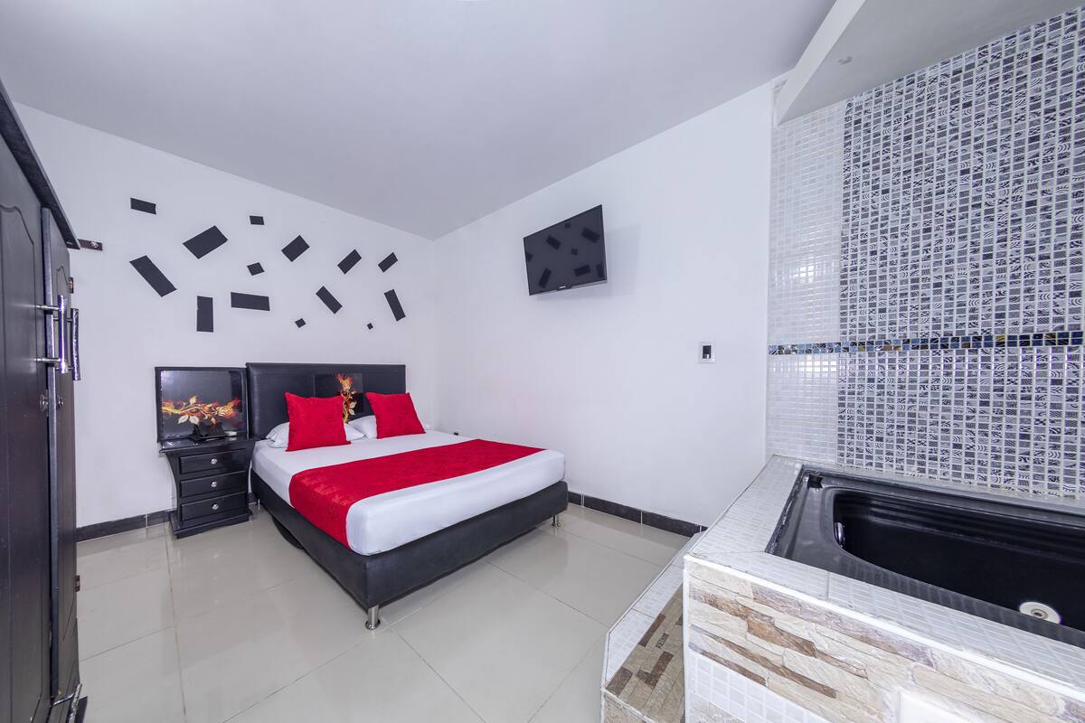 Ein modernes Schlafzimmer mit Bett, Fernseher und einem Badezimmer mit Badewanne.