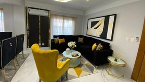 Een moderne woonkamer met een zwarte bank, een gele fauteuil en een ronde salontafel.