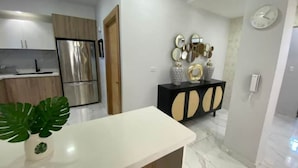 Een moderne keuken met roestvrijstalen apparatuur, een wit aanrecht en een decoratieve console met spiegels en vazen.
