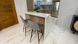 Een moderne keuken met een centraal eiland, barstoelen en een koelkast.