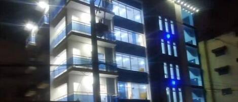 A multi-story building with illuminated windows and balconies at night.