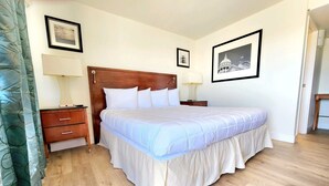 A neatly arranged bedroom with a large bed, wooden headboard, two bedside tables with lamps, and framed pictures on the walls.