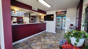 A reception area with a maroon counter, a sign for 'EXTENDED RESIDENCE INN & SUITES', and a tiled floor.