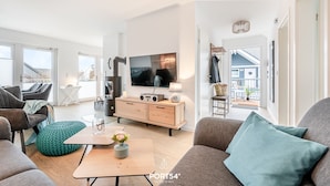 Un salon moderne avec un canapé, une table basse, un téléviseur et une cheminée.