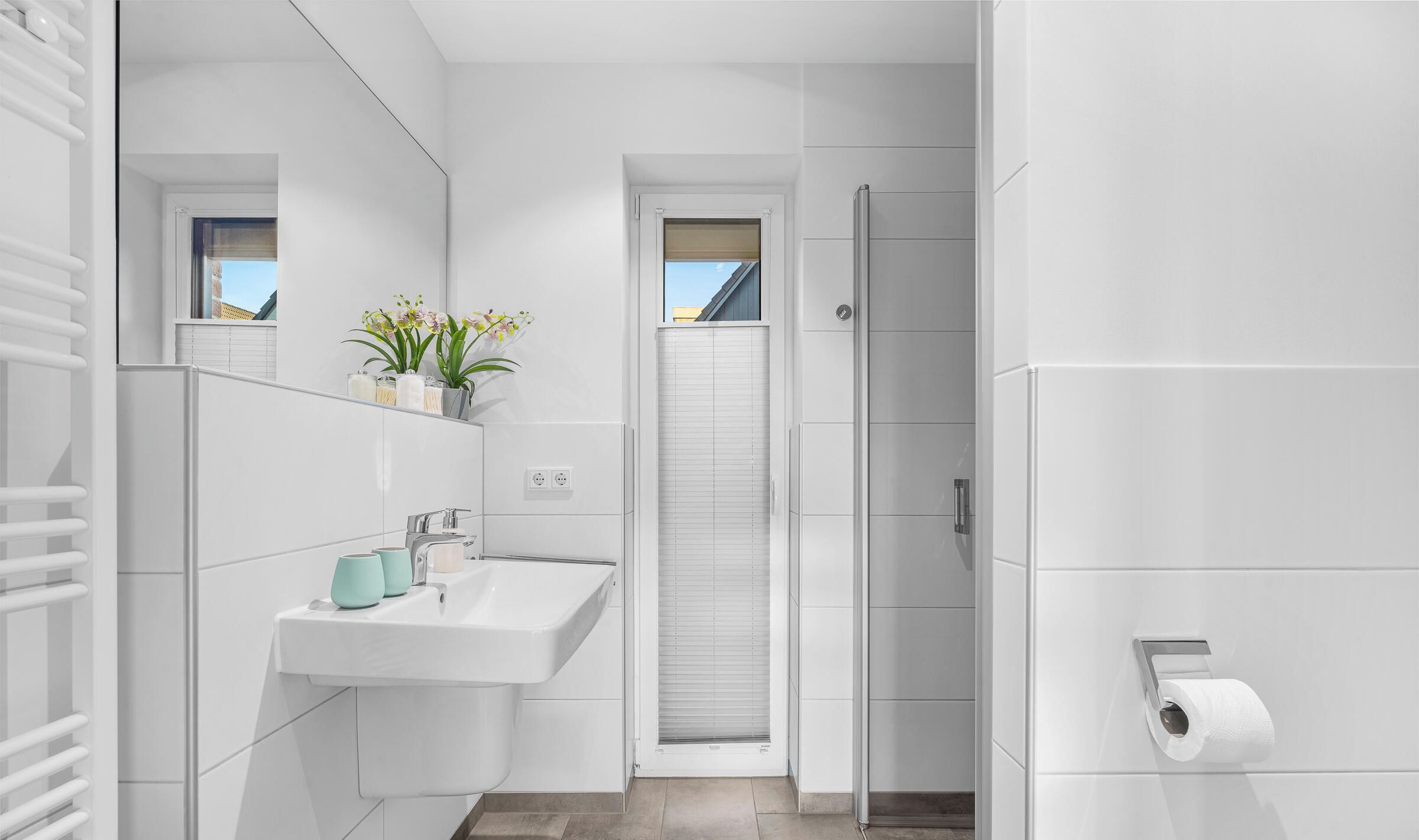 Ein modernes Badezimmer mit einem weißen Waschbecken, einem Spiegel und einer Toilette.