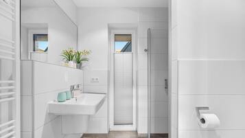 Ein modernes Badezimmer mit einem weißen Waschbecken, einem Spiegel und einer Toilette.