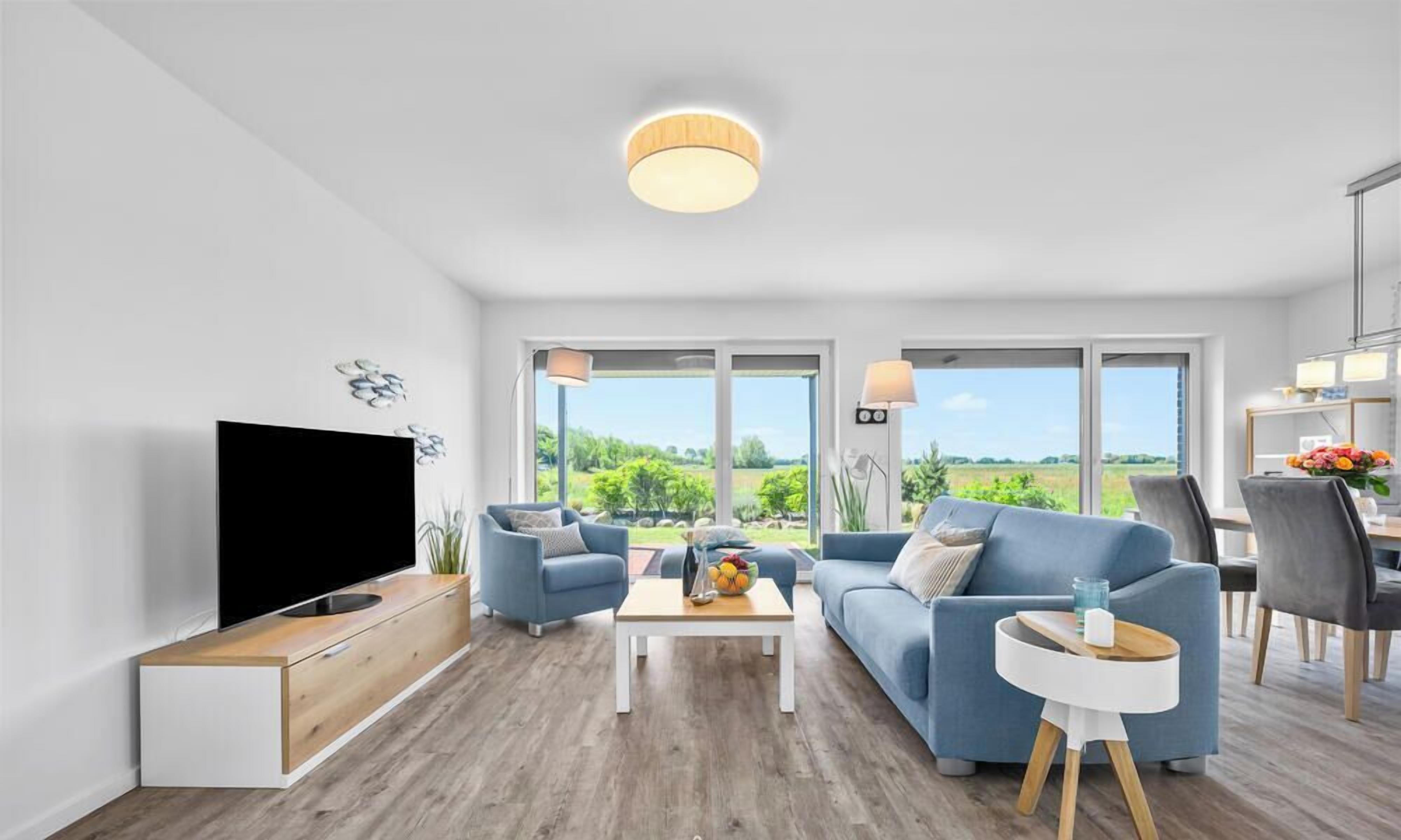 Een moderne woonkamer met een flatscreen televisie, twee banken, een salontafel en een eethoek met stoelen.