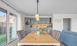 A modern kitchen with grey cabinets, a wooden dining table, and a blue sofa.