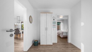 Un intérieur moderne avec un plancher en bois, des murs blancs, une armoire et un coin repas comprenant des chaises et une table.