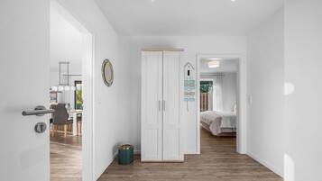 A modern interior with a wooden floor, white walls, a wardrobe, and a dining area with chairs and a table.