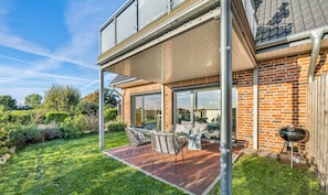 A two-story house with a patio, outdoor seating, and a barbecue grill. - Ferienwohnung Meerverliebt Büsum (Westerdeichstrich)
