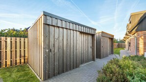 Un bâtiment moderne doté d’une façade en bois, d’un chemin pavé et d’une zone herbeuse.