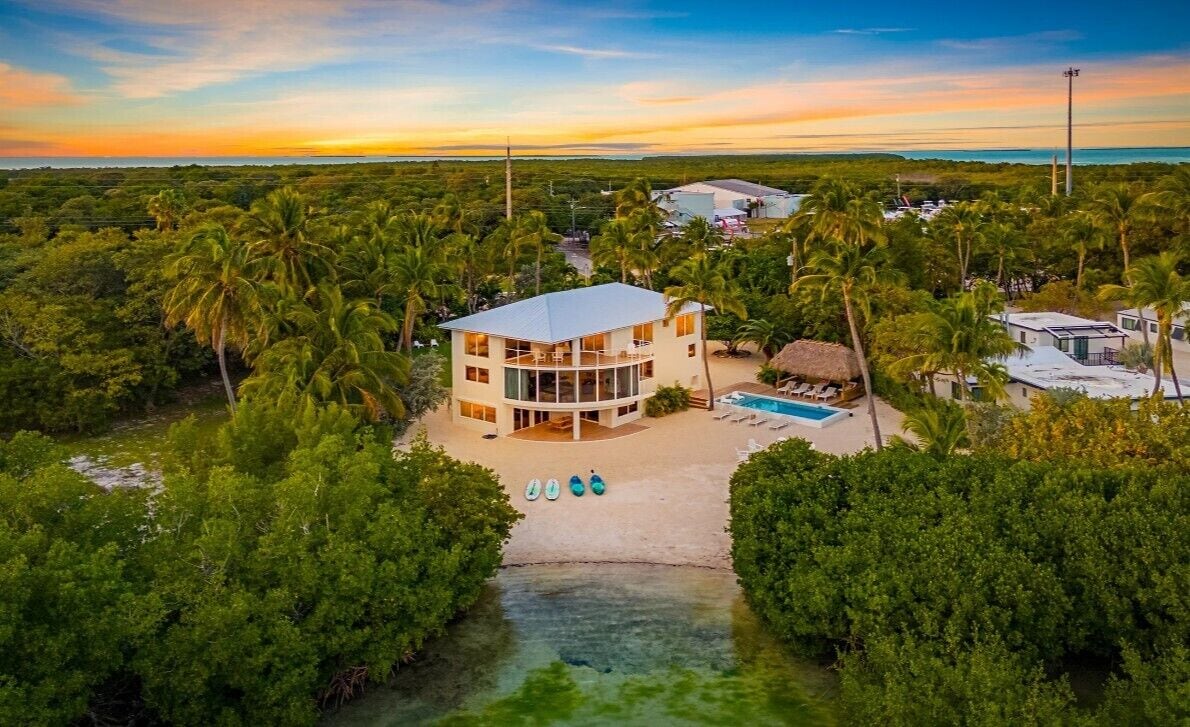 Un immeuble à plusieurs étages doté d’une piscine, entouré d’une végétation tropicale luxuriante.