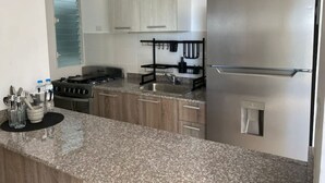 Eine moderne Küche mit Granit Arbeitsplatten, Edelstahlgeräten und Holzschränken.