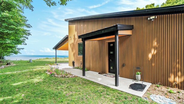 Ein modernes Haus mit Holzfassade, einer überdachten Veranda und Blick auf das Meer.