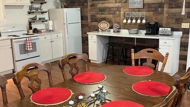A dining area with a wooden table and chairs, a kitchen in the background, and a wall with a wooden panel design. - X Marks the Spot (Purple) (Santa Claus)