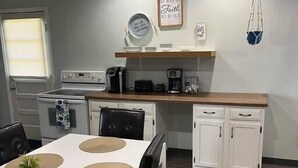 Une cuisine moderne avec un coin repas, comprenant un four blanc, des appareils électroménagers noirs et un plan de travail en bois.
