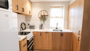 Een moderne keuken met houten kastjes, een inbouwoven, een magnetron, een broodrooster en een spoelbak.