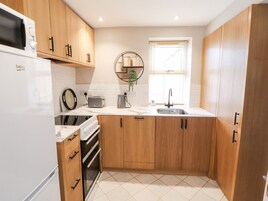 Una cocina moderna con armarios de madera, horno empotrado, microondas, tostadora y un lavabo.
