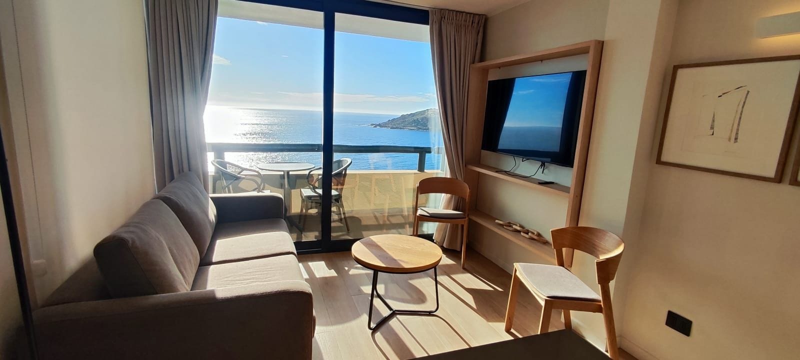 A balcony with a sofa, chairs, and a TV.