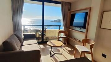 A balcony with a sofa, chairs, and a TV.